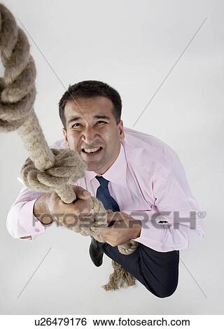 Businessman trying to climb a rope View Large Photo Image Stock Photograph - Businessman trying to climb a rope. Fotosearch