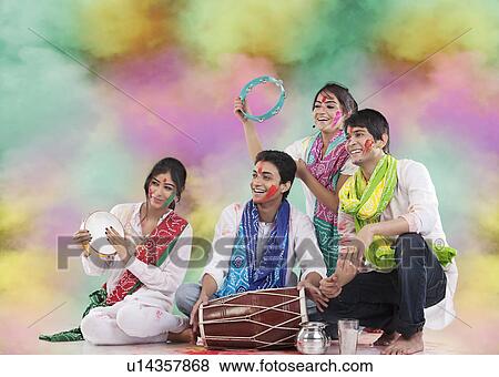 Stock Photo - Friends playing music during holi. Fotosearch