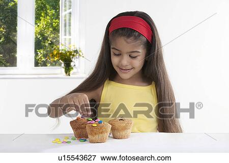 Girl decorating muffins View Large Photo Image Stock Photo - Girl decorating muffins. Fotosearch