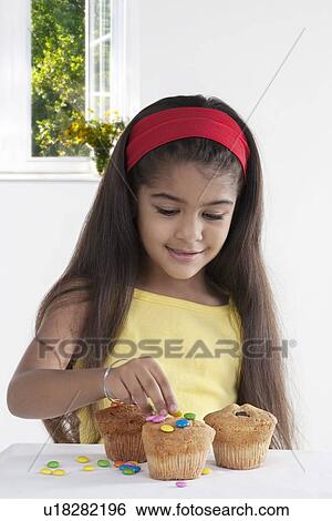 Stock Photograph - Girl decorating muffins. Fotosearch