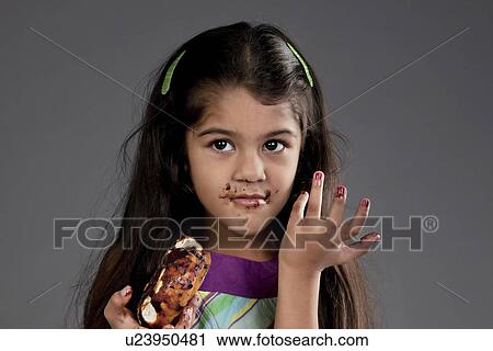 Stock Image - Girl eating a chocolate doughnut. Fotosearch