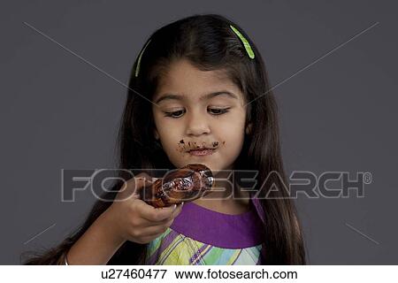 Stock Photo - Girl eating a chocolate doughnut. Fotosearch