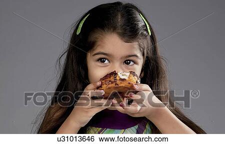 Girl eating a chocolate doughnut View Large Photo Image Stock Photograph - Girl eating a chocolate doughnut. Fotosearch