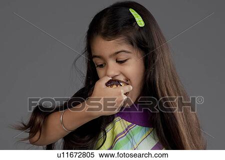 Girl eating a chocolate doughnut View Large Photo Image Stock Photography - Girl eating a chocolate doughnut. Fotosearch