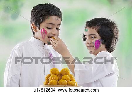 Girl feeding laddoo to a boy View Large Photo Image Picture - Girl feeding laddoo to a boy. Fotosearch