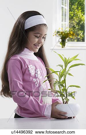 Stock Image - Girl holding a potted plant. Fotosearch