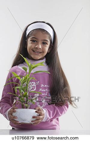 Girl holding a potted plant View Large Photo Image Stock Photo - Girl holding a potted plant. Fotosearch