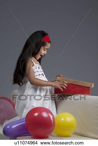 Picture - Girl opening gifts. Fotosearch