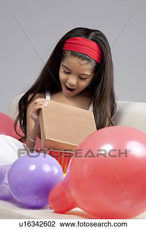 Stock Image - Girl opening gifts. Fotosearch