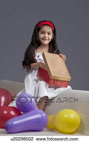 Stock Image - Girl opening gifts. Fotosearch