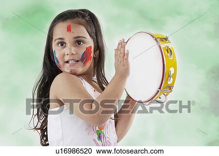 Stock Image - Girl playing on a tambourine. Fotosearch