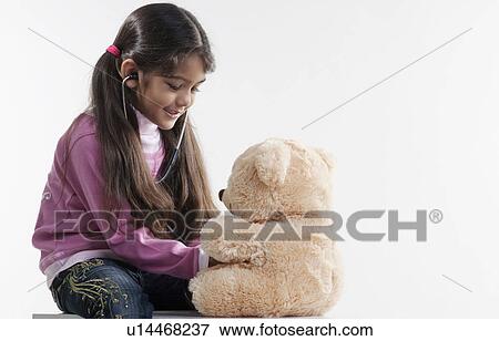 Stock Photo - Girl playing with a teddy bear. Fotosearch