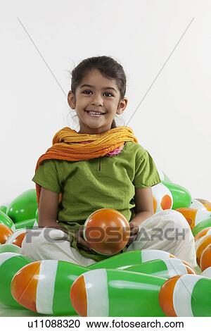 Stock Image - Girl sitting with balloons. Fotosearch