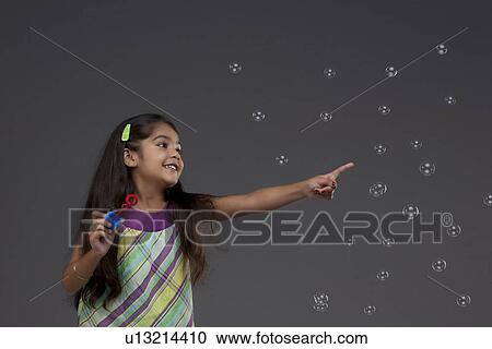 Stock Image - Girl trying to touch a bubble. Fotosearch