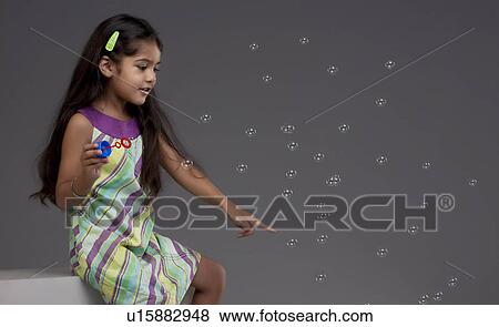 Stock Photo - Girl trying to touch a bubble. Fotosearch