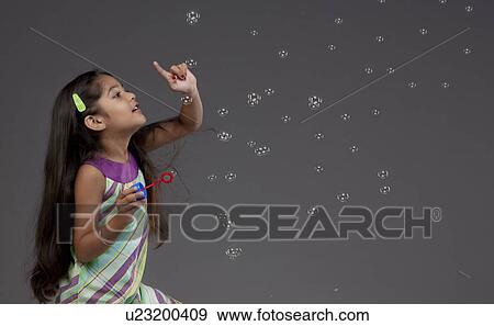 Stock Photo - Girl trying to touch a bubble. Fotosearch