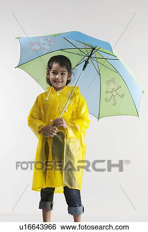 Stock Photograph - Girl wearing a raincoat and holding an umbrella. Fotosearch