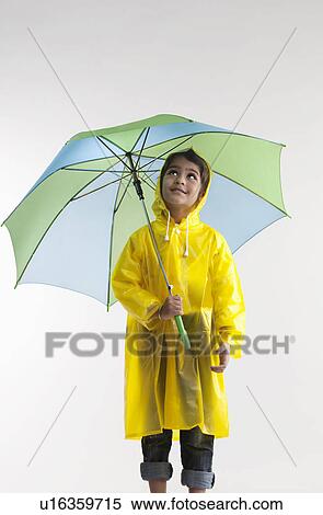 Stock Photography - Girl wearing a raincoat and holding an umbrella. Fotosearch