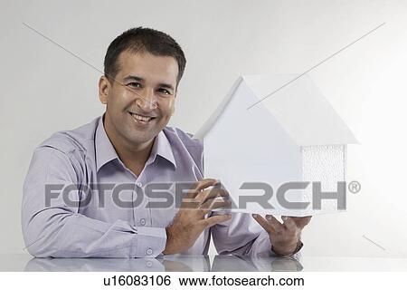 Stock Photograph - Man holding a house model. Fotosearch