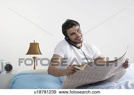 Man holding a newspaper and talking on the phone View Large Photo Image Stock Photo - Man holding a newspaper and talking on the phone. Fotosearch