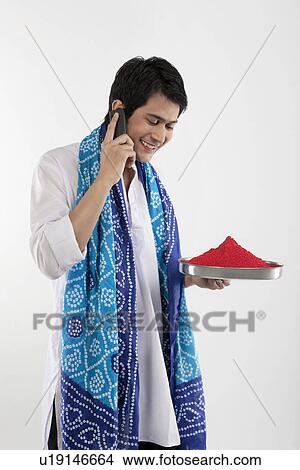 Picture - Man holding a tray of colours while talking on a mobile phone. Fotosearch