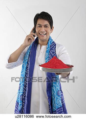 Stock Photograph - Man holding a tray of colours while talking on a mobile phone. Fotosearch