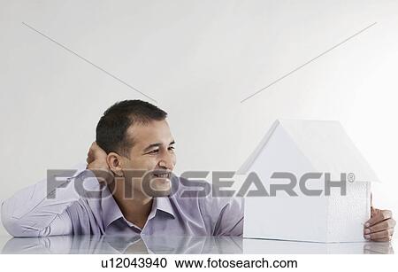 Stock Image - Man looking at a house model. Fotosearch