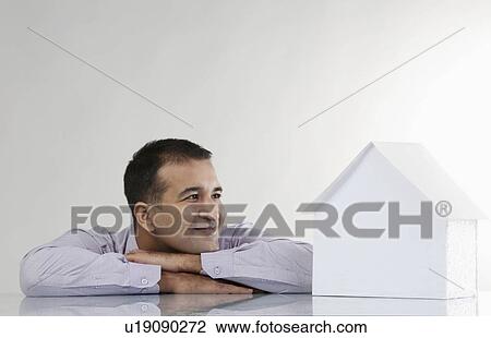 Stock Image - Man looking at a house model. Fotosearch