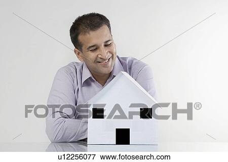 Man looking at a house model View Large Photo Image Stock Photo - Man looking at a house model. Fotosearch