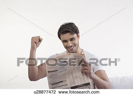 Stock Image - Man rejoicing after reading newspaper. Fotosearch