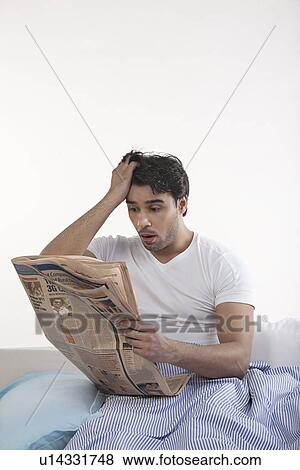 Stock Photo - Man shocked after reading newspaper. Fotosearch