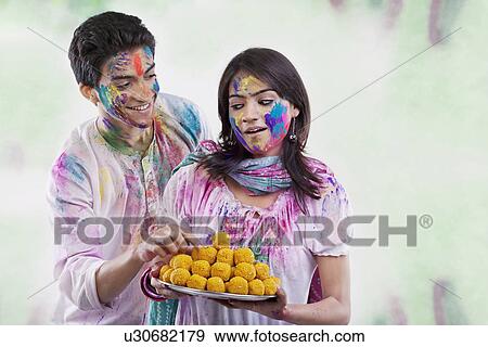 Stock Photo - Man taking a laddoo from a tray. Fotosearch