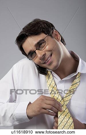 Man tying a tie while talking on the phone View Large Photo Image Stock Image - Man tying a tie while talking on the phone. Fotosearch