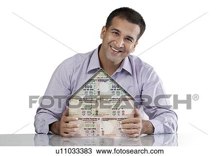 Stock Image - Man with a house model. Fotosearch