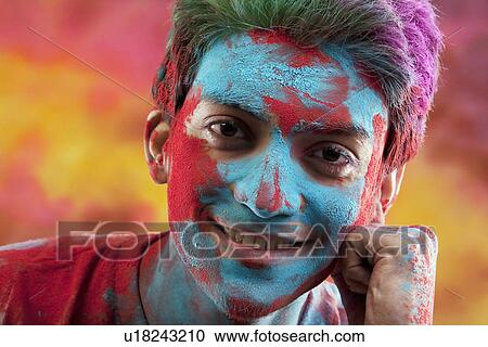 Stock Image - Man's face covered in holi colours. Fotosearch
