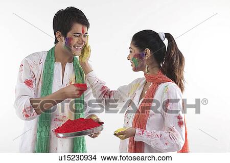 Picture - Woman putting colour on a man's face. Fotosearch