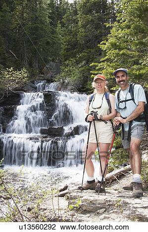Stock Image - Couple hiking near a waterfall. Fotosearch