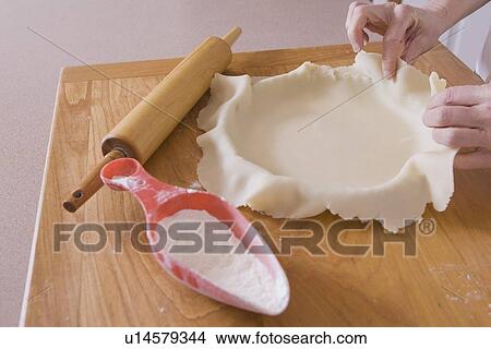 covering pie pan with dough on a cutting board with rolling pin and flour View Large Photo Image Picture - covering pie pan with dough on a cutting board with rolling pin and flour. Fotosearch