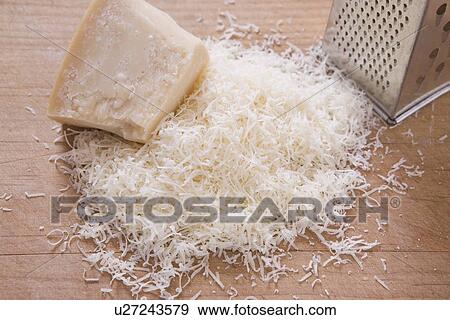 Stock Photo - shredded parmeson cheese on a cutting board with a grater. Fotosearch