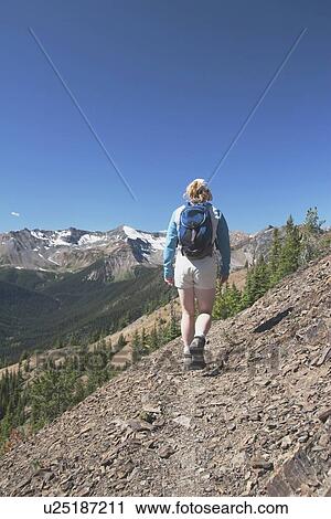 Stock Image - Woman hiking on a mountain trail. Fotosearch