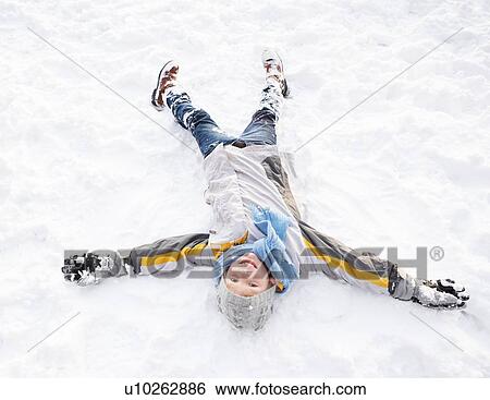 Stock Photograph - Boy Laying On Ground Making Snow Angel. Fotosearch