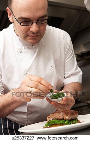 Stock Photo - Chef Adding Seasoning To Dish In Restaurant Kitchen. Fotosearch