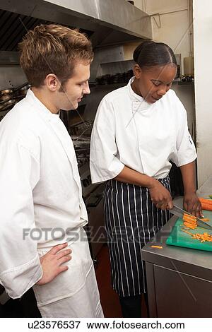 Stock Photo - Chef Instructing Trainee In Restaurant Kitchen. Fotosearch