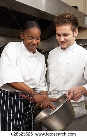 Stock Photograph - Chef Instructing Trainee In Restaurant Kitchen. Fotosearch