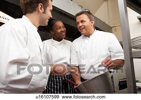 Stock Photo - Chef Instructing Trainees In Restaurant Kitchen. Fotosearch