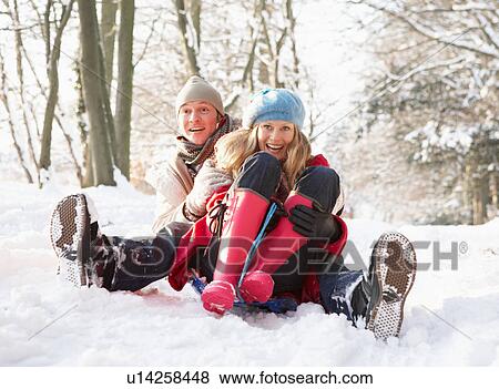Stock Photo - Couple Sledging Through Snowy Woodland. Fotosearch