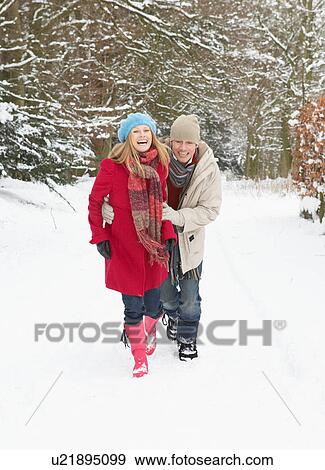 Stock Photo - Couple Walking Through Snowy Woodland. Fotosearch
