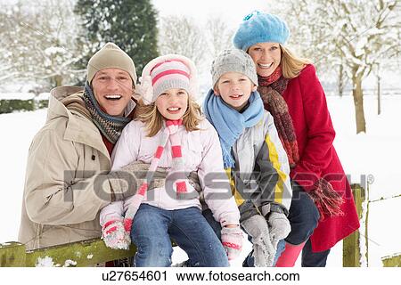 Stock Image - Family Sitting In Snowy Landscape. Fotosearch