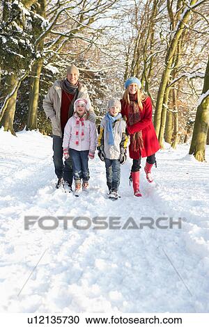 Stock Image - Family Walking Through Snowy Woodland. Fotosearch