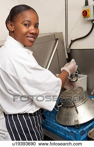 Stock Image - Kitchen Worker Washing Up In Restaurant Kitchen. Fotosearch